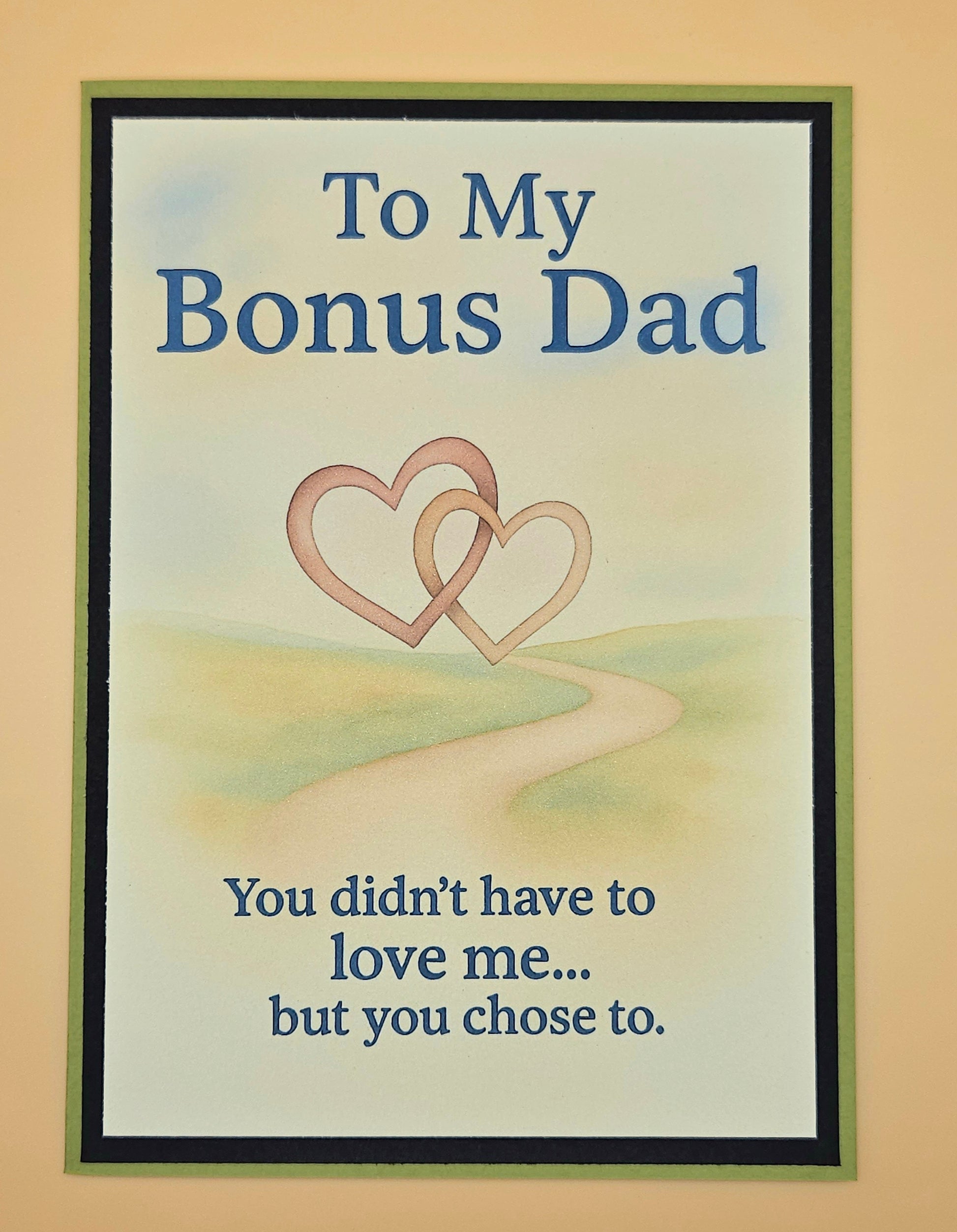 Framed artwork with two interlocking hearts and text 'To My Bonus Dad' on a beige background
