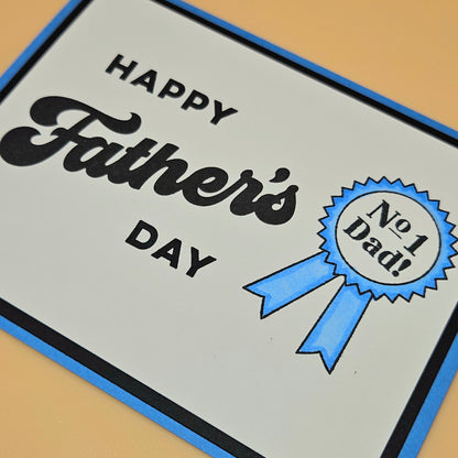 Father's Day card with 'Happy Father's Day' text and a blue ribbon badge on a beige background.