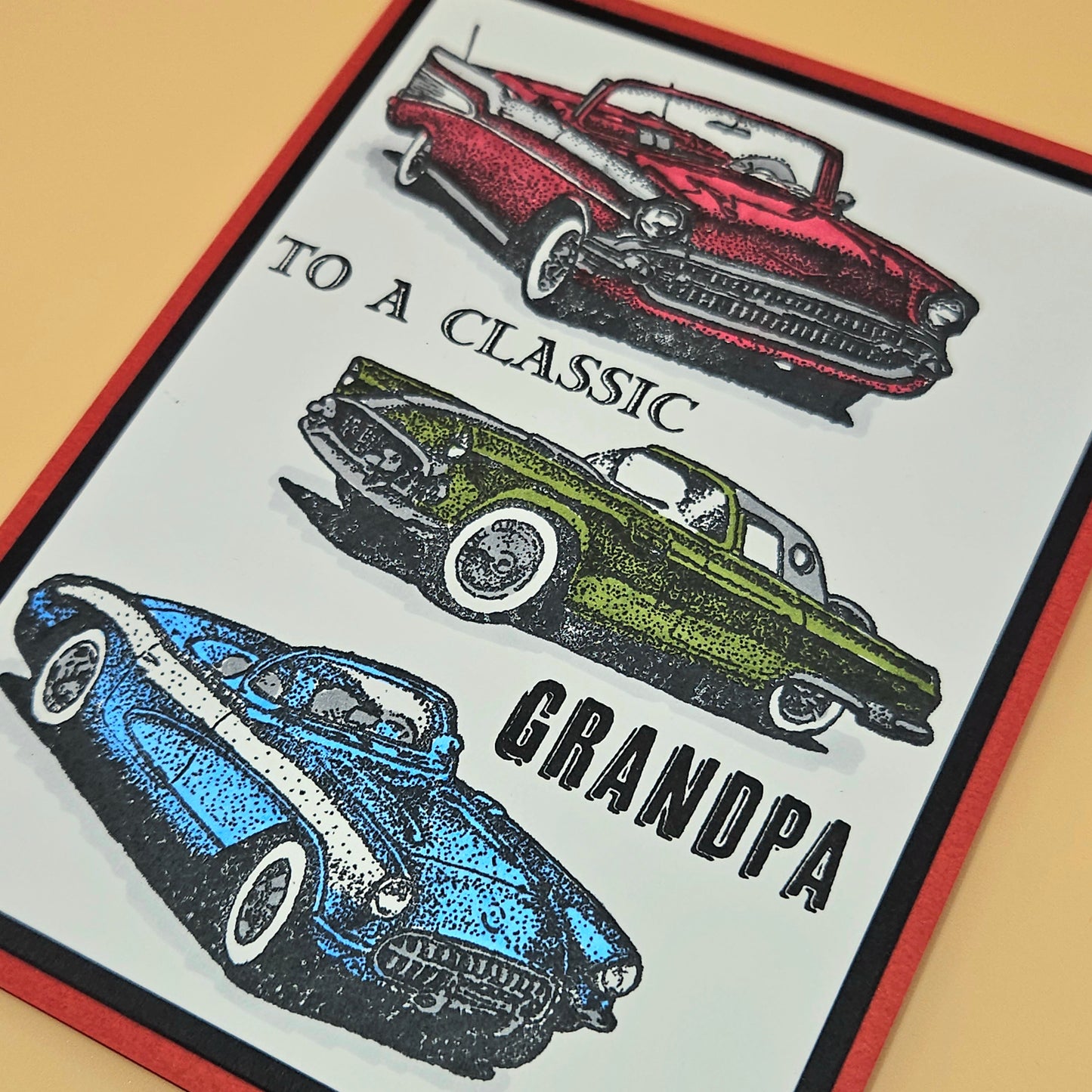 Close up of hand-colored vintage car illustrations including red convertible olive coupe and blue Corvette