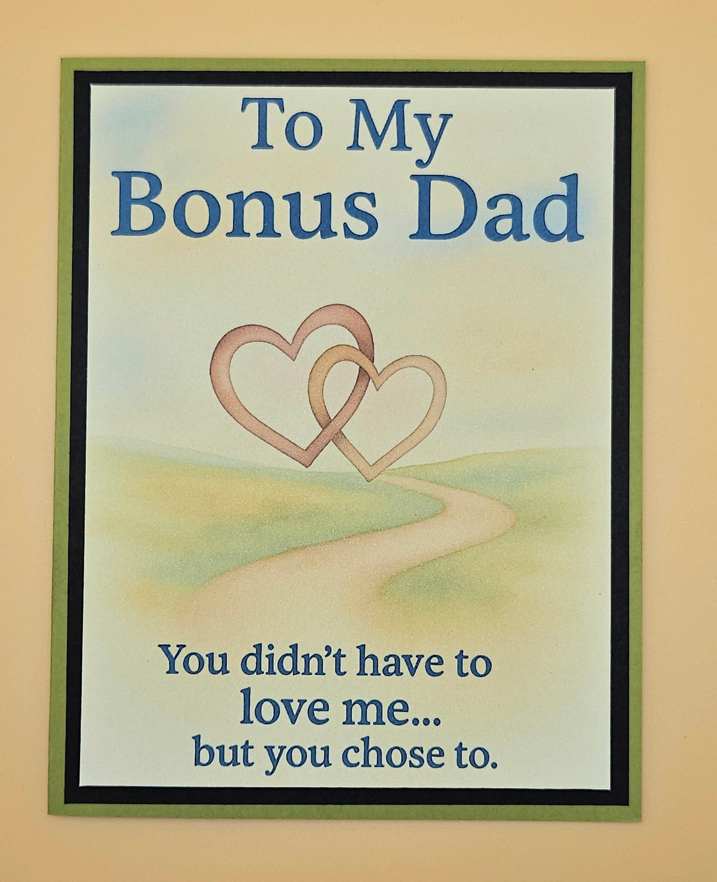 Framed artwork with two interlocking hearts and text about a bonus dad on a beige background