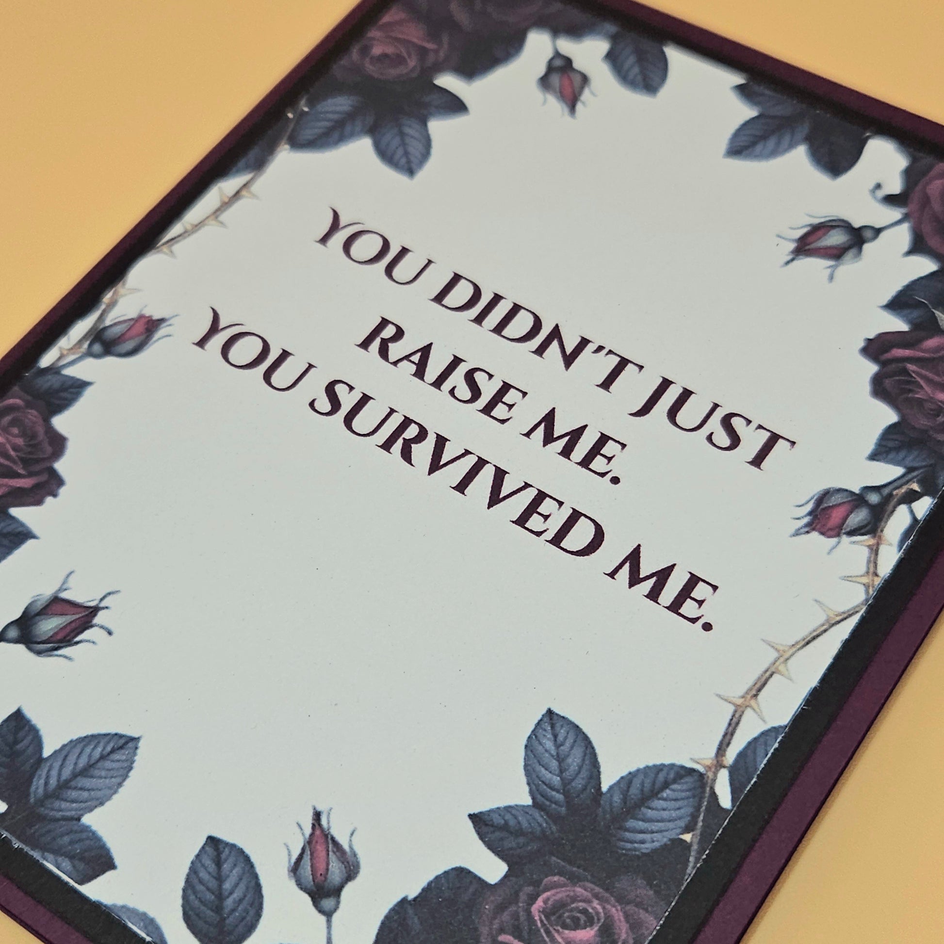 Card with floral design and text 'You didn't just raise me. You survived me.' on a beige background