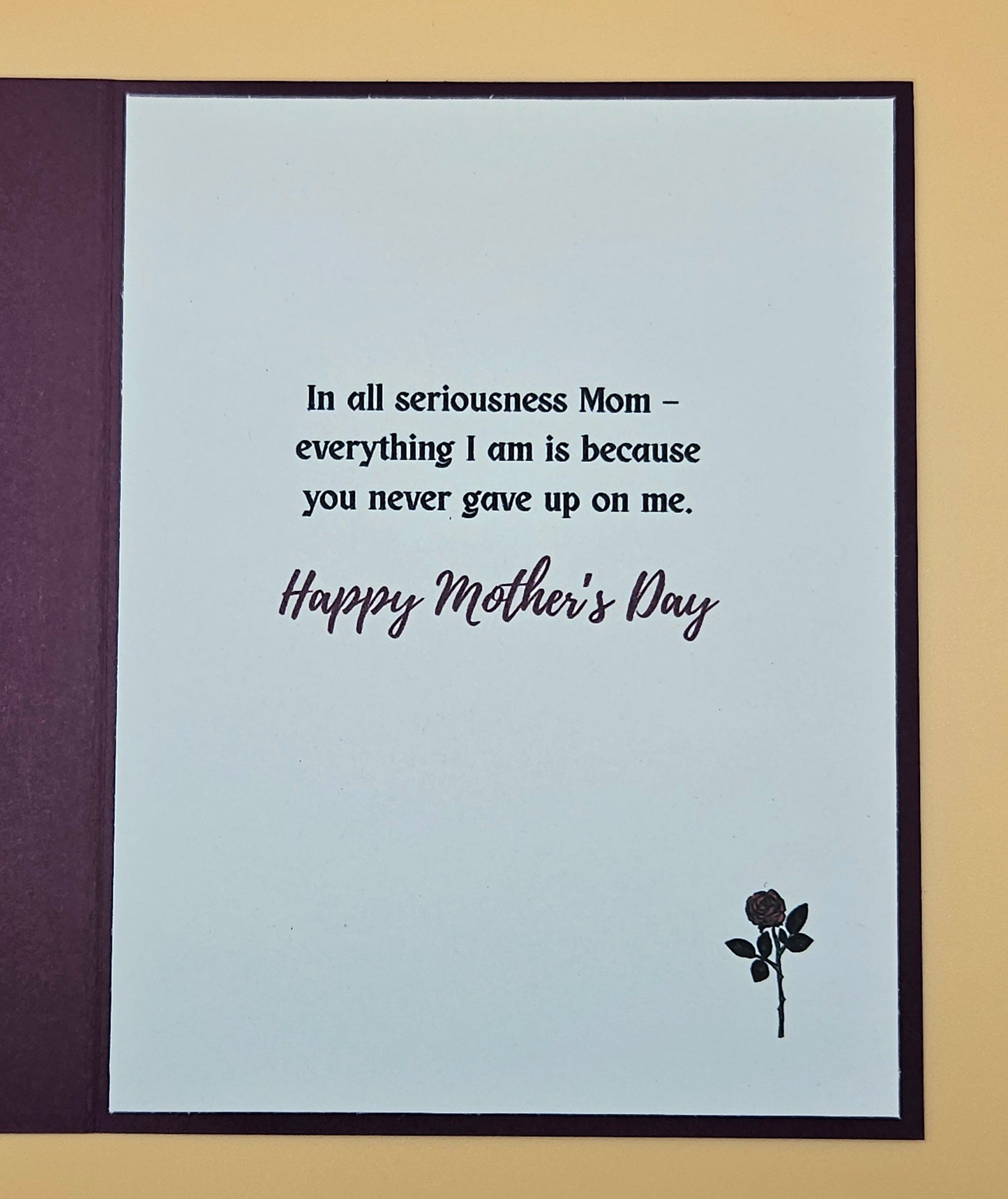 Card with Mother's Day message and rose on a plain background