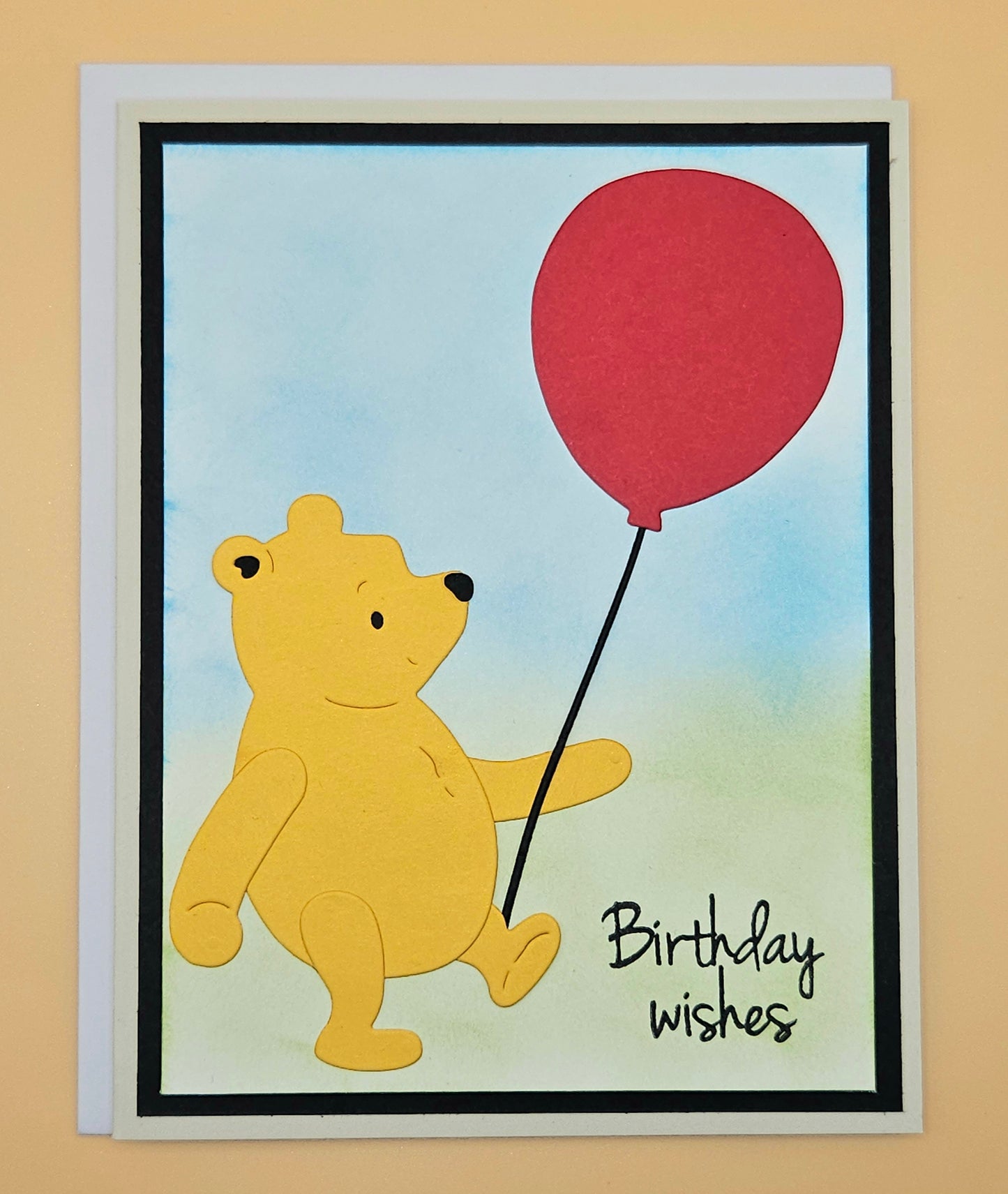 Card with a bear holding a red balloon and 'Birthday wishes' text on a beige background