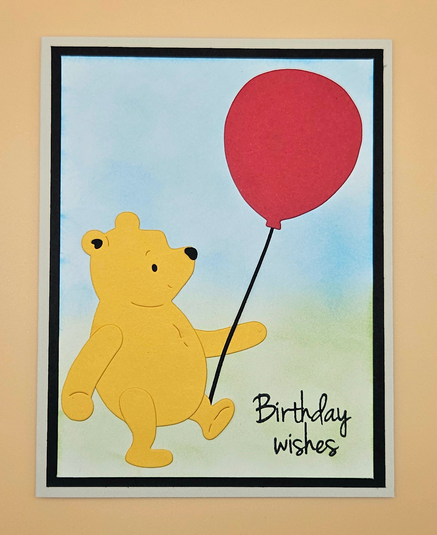 Card with a bear holding a red balloon and 'Birthday wishes' text on a beige background