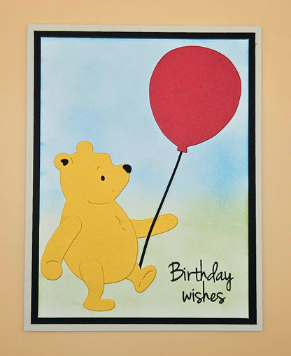 Card with a bear holding a red balloon and 'Birthday wishes' text on a beige background