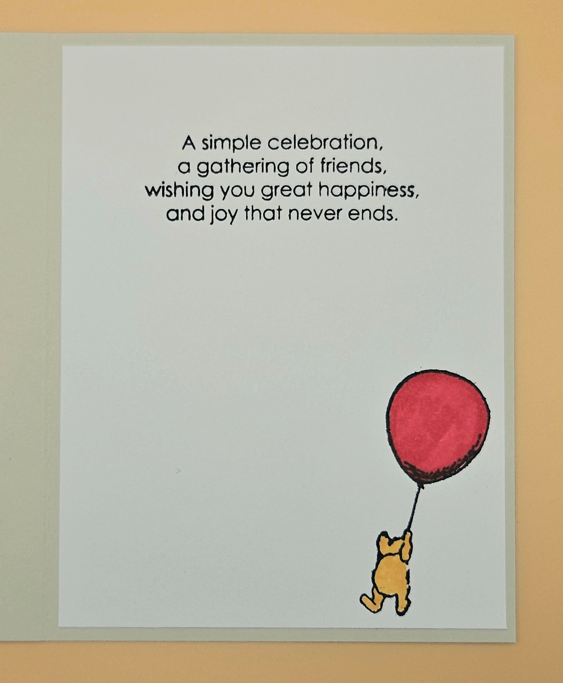 Card with Winnie the Pooh holding a red balloon and text on a beige background
