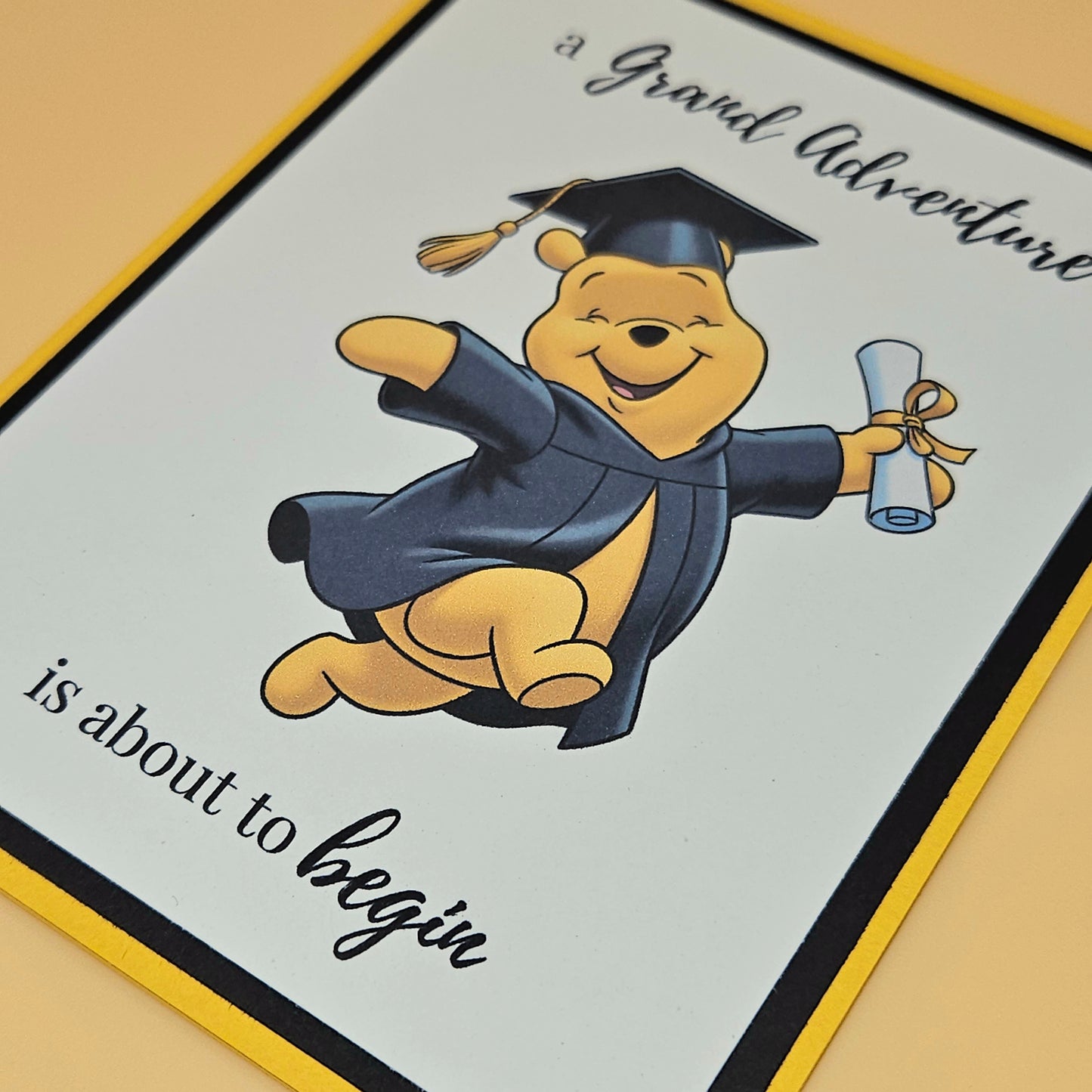 Graduation-themed card with a cartoon bear in a cap and gown holding a diploma.