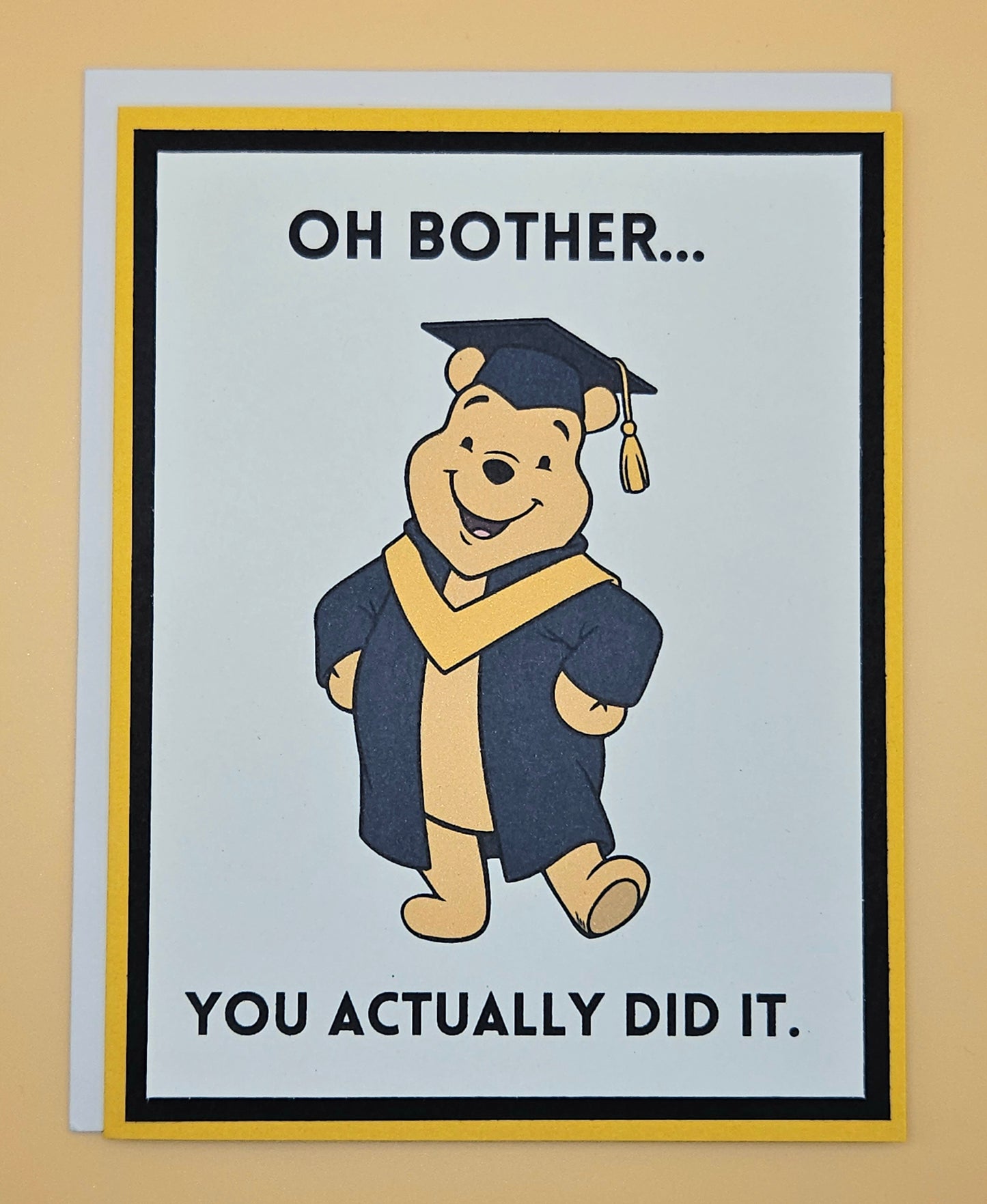 Graduation-themed card with cartoon bear in cap and gown on a beige background