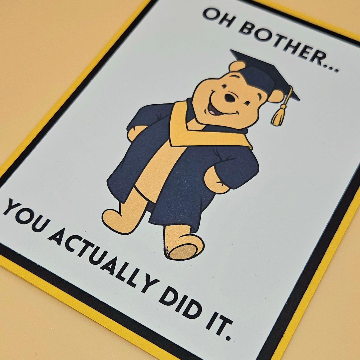 Cartoon bear in graduation attire with humorous text on a card