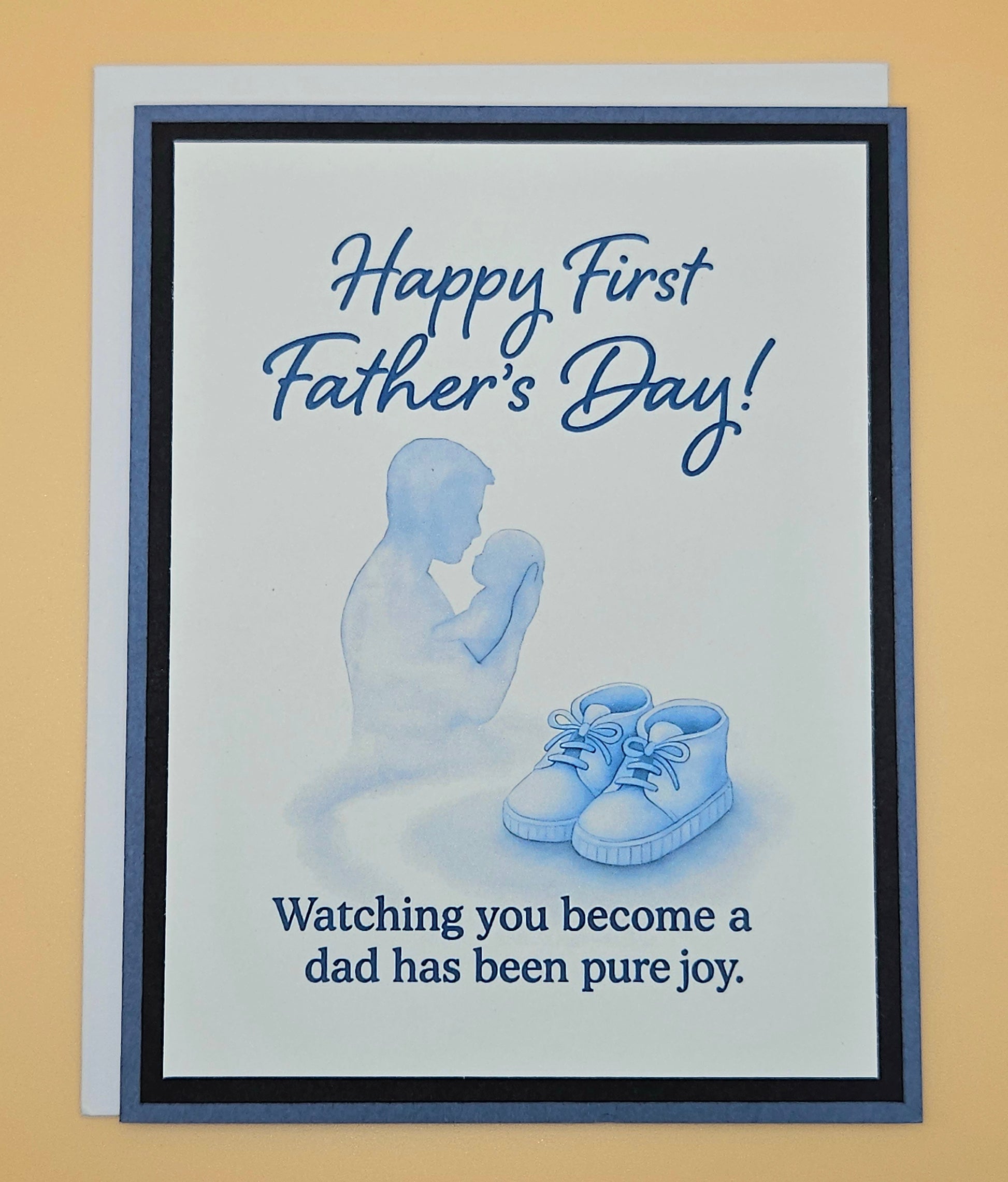 Father's Day card with silhouette of a father and baby shoes, text 'Happy First Father's Day! Watching you become a dad has been pure joy.'.