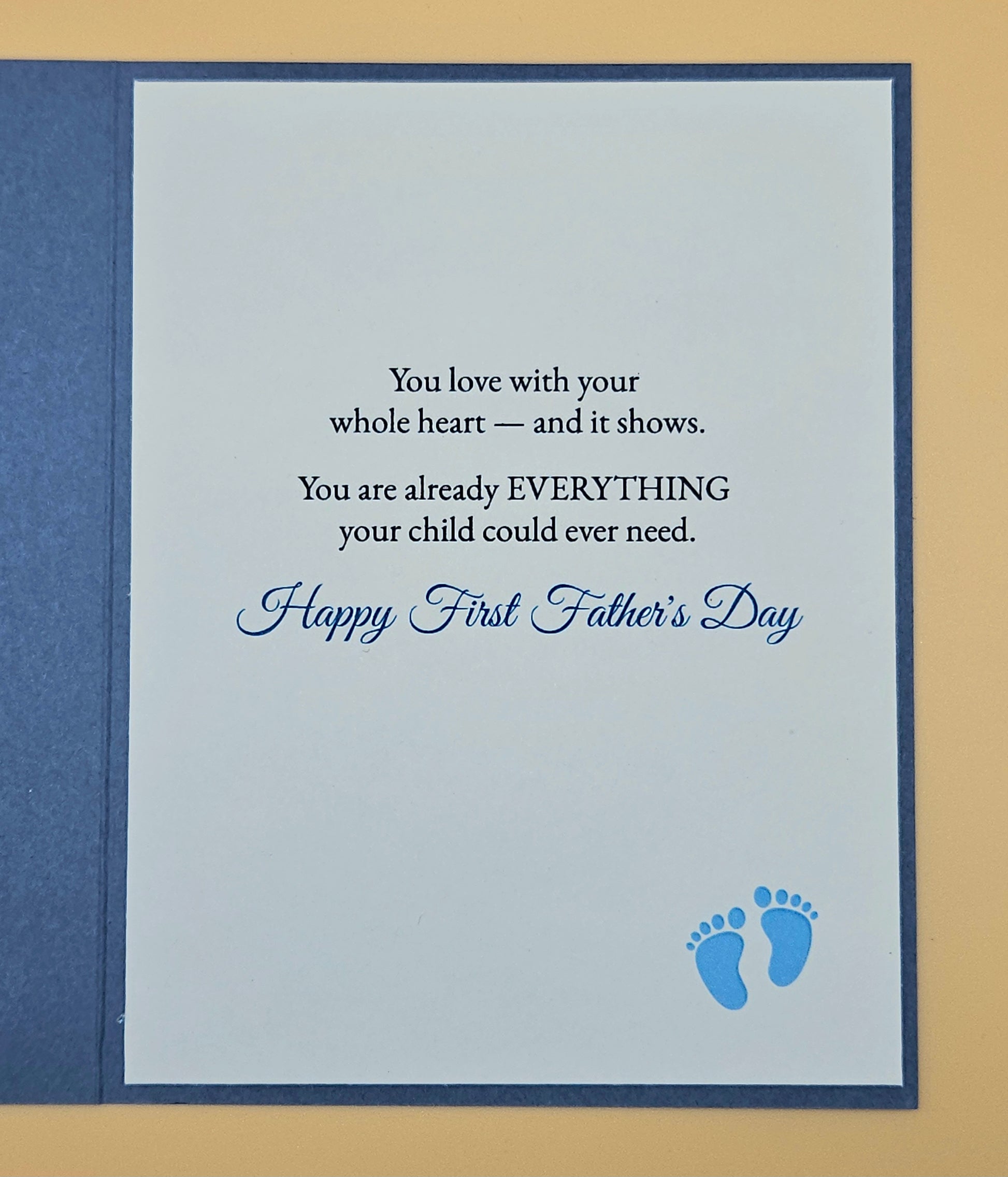 Father's Day card with text and blue footprints on a beige background