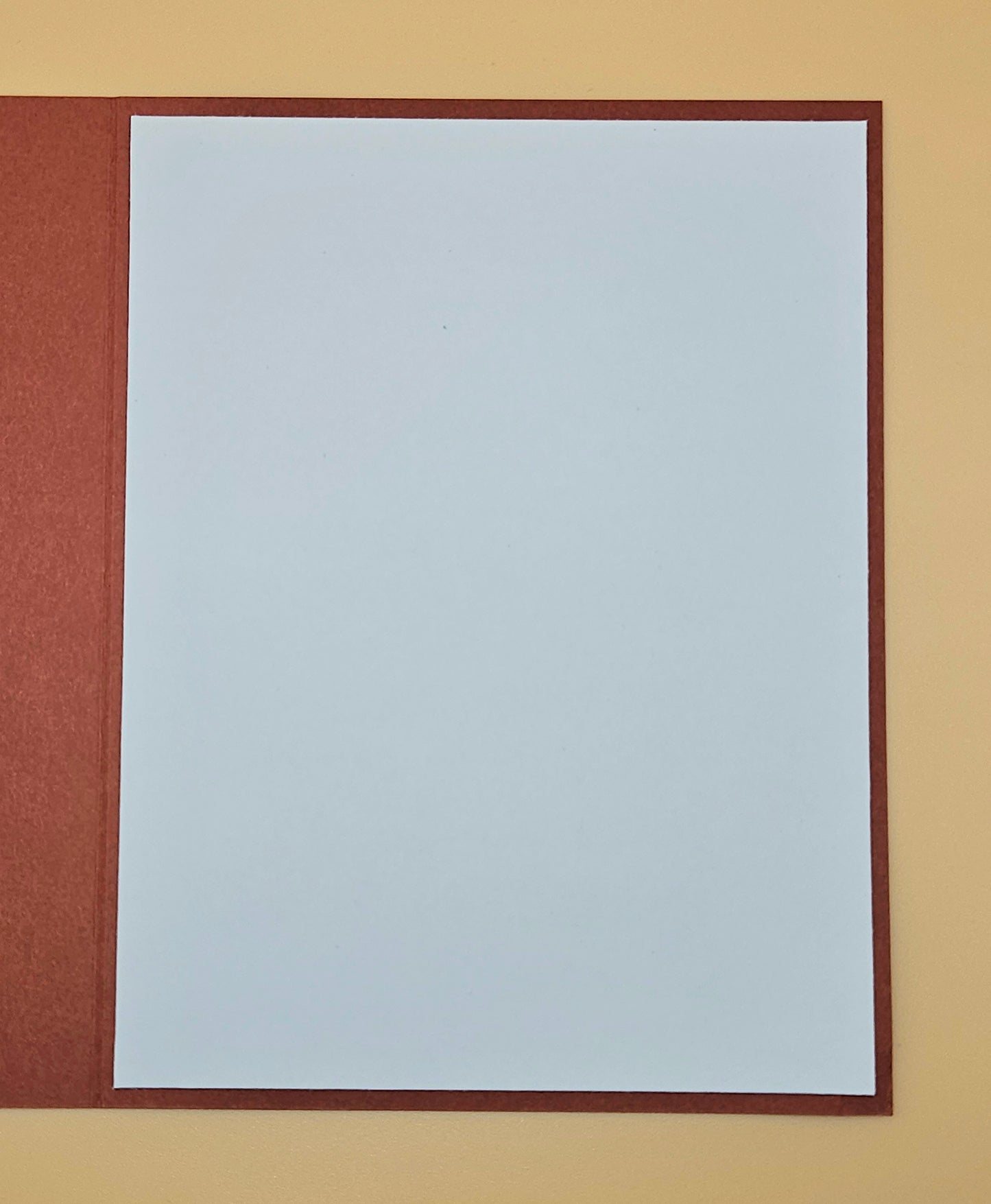Plain white sheet of paper with a brown border on a beige background