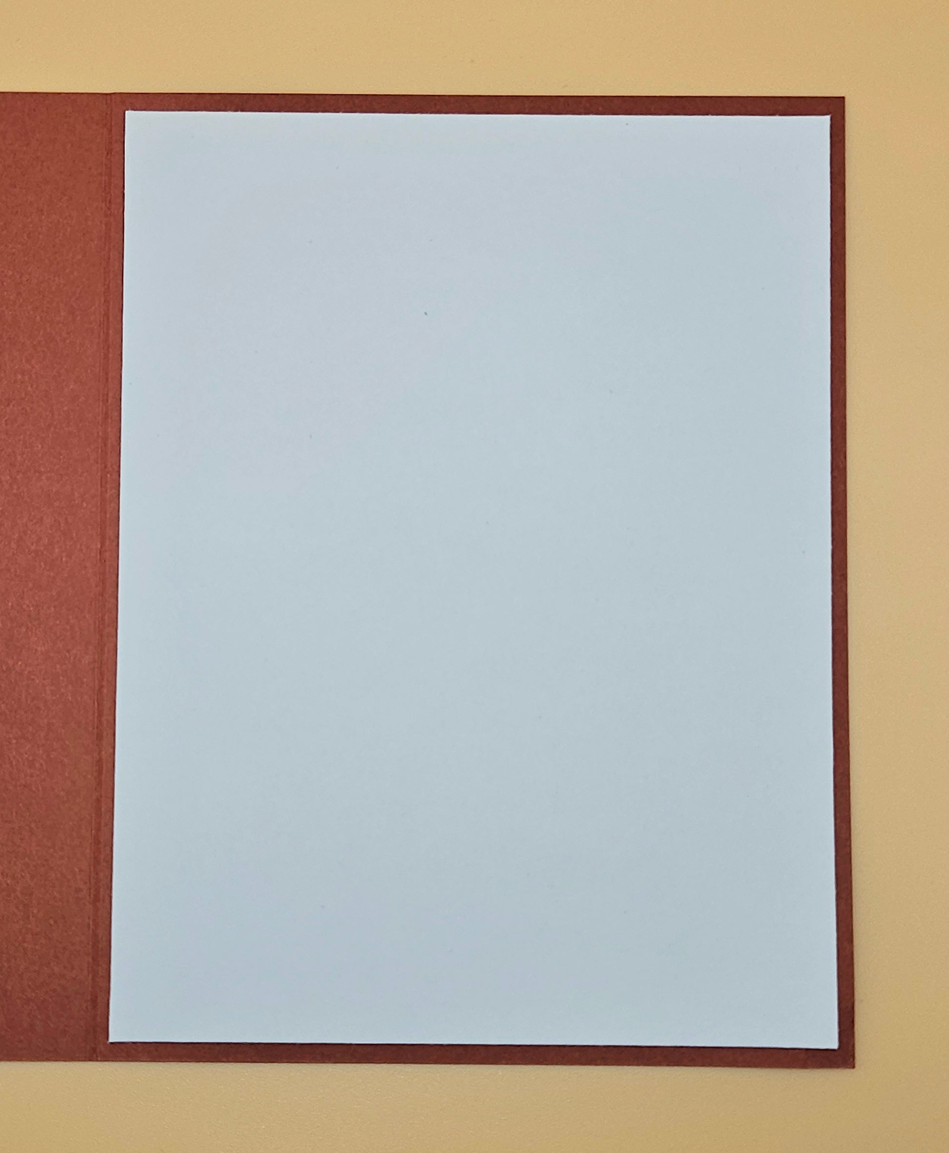 Plain white sheet of paper with a brown border on a beige background