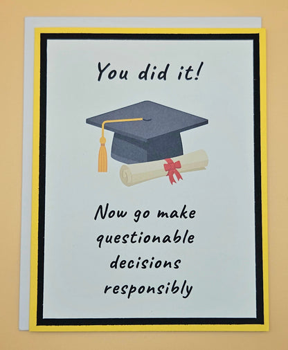 Handmade funny graduation card with mortarboard and diploma on white panel with black and yellow border. Front reads You Did It Now Go Make Questionable Decisions Responsibly.