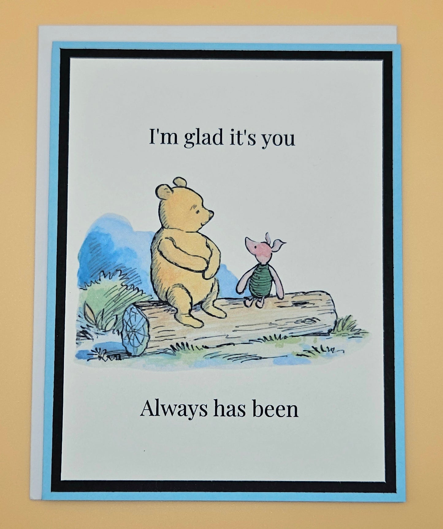 Handmade Winnie the Pooh and Piglet friendship card with Pooh and Piglet sitting on a log in watercolor style on white inner panel with black and sky blue border. Text reads I'm glad it's you always has been.