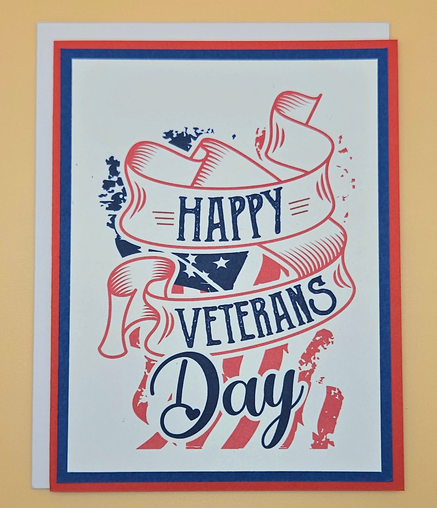 Handmade Veterans Day card with bold patriotic ribbon banner and stars and stripes design on white inner panel with black navy and red borders. Text reads Happy Veterans Day. TiddlyPomCards.com