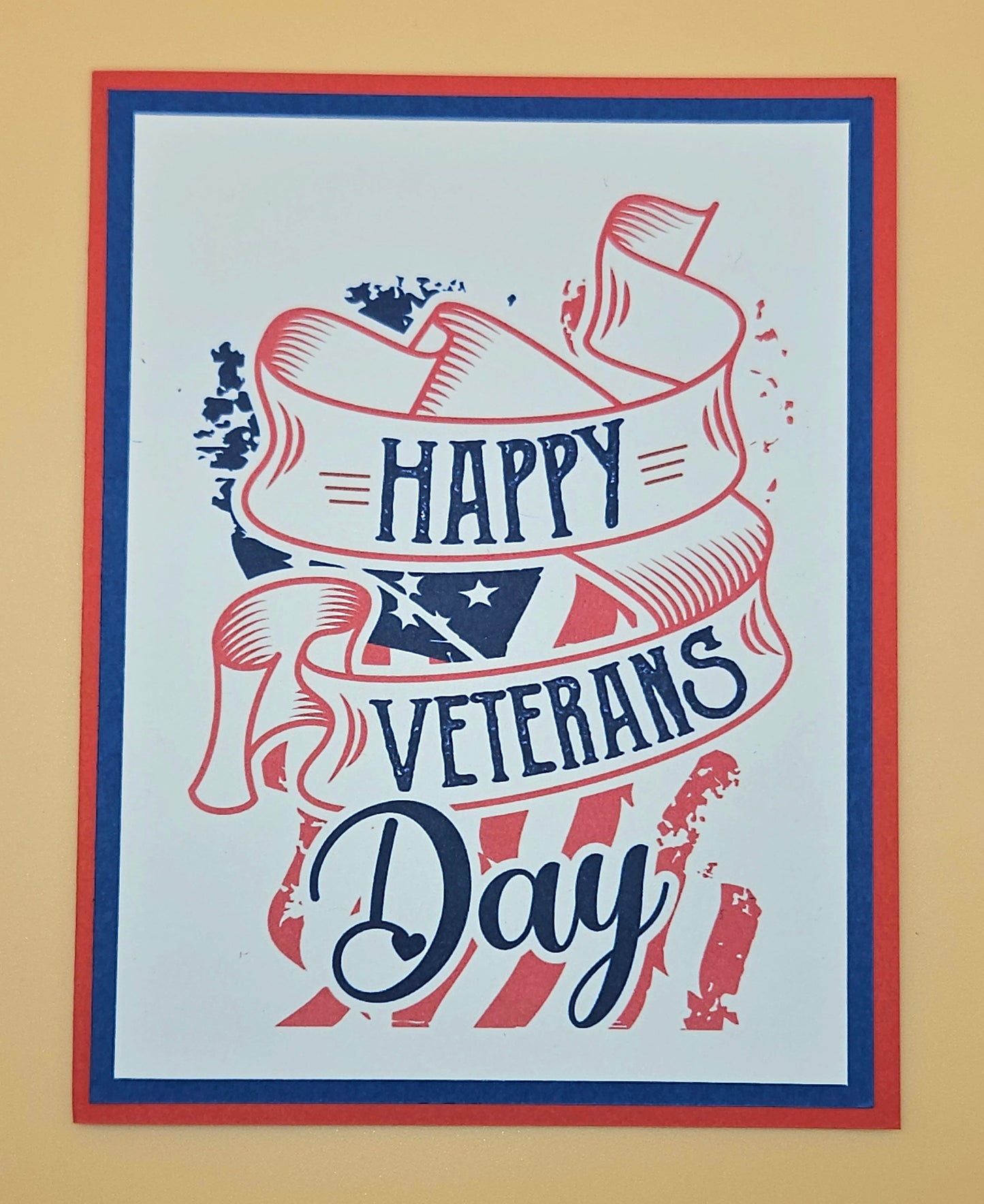 Handmade Veterans Day card with bold patriotic ribbon banner and stars and stripes design on white inner panel with black navy and red borders. Text reads Happy Veterans Day. TiddlyPomCards.com