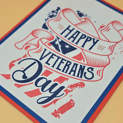 Handmade Veterans Day card with bold patriotic ribbon banner and stars and stripes design on white inner panel with black navy and red borders. Text reads Happy Veterans Day. TiddlyPomCards.com