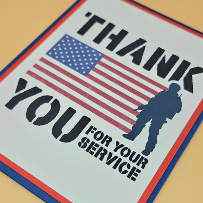 Handmade Veterans Day card with bold military stencil typography American flag and soldier silhouette on white inner panel with red and navy borders. Text reads Thank You for Your Service.