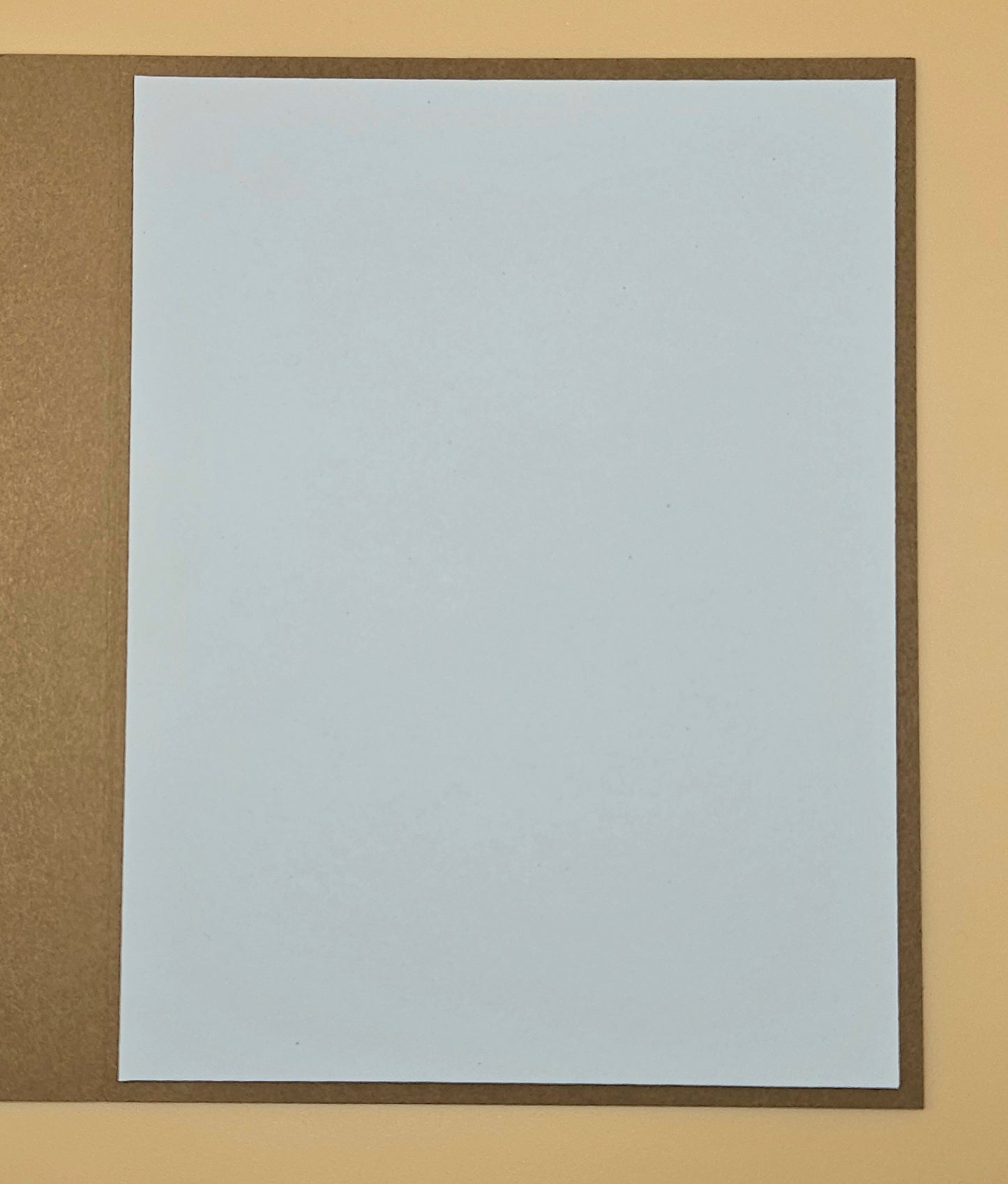 Plain white sheet of paper with a brown border on a beige background