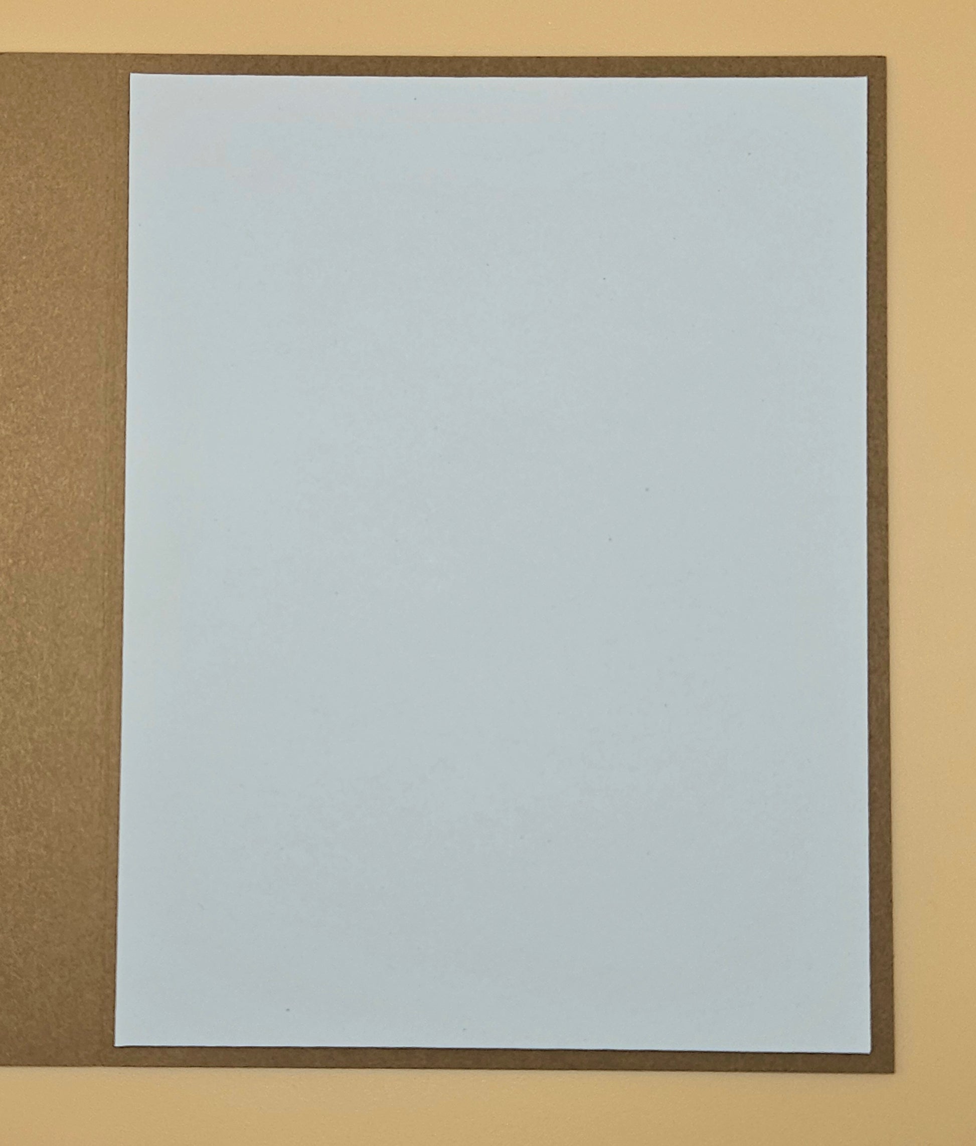Plain white sheet of paper with a brown border on a beige background