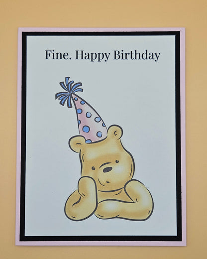 Handmade funny Winnie the Pooh birthday card with grumpy Pooh sitting arms crossed wearing a pink polka dot party hat on white inner panel with black and pink border. Text reads Fine Happy Birthday.