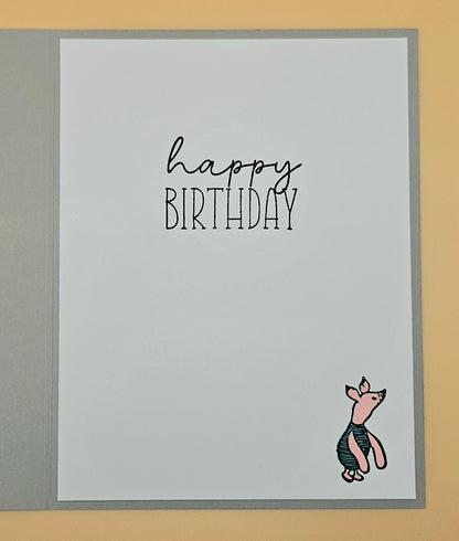 Birthday card with 'happy birthday' text and piglet on a gray background