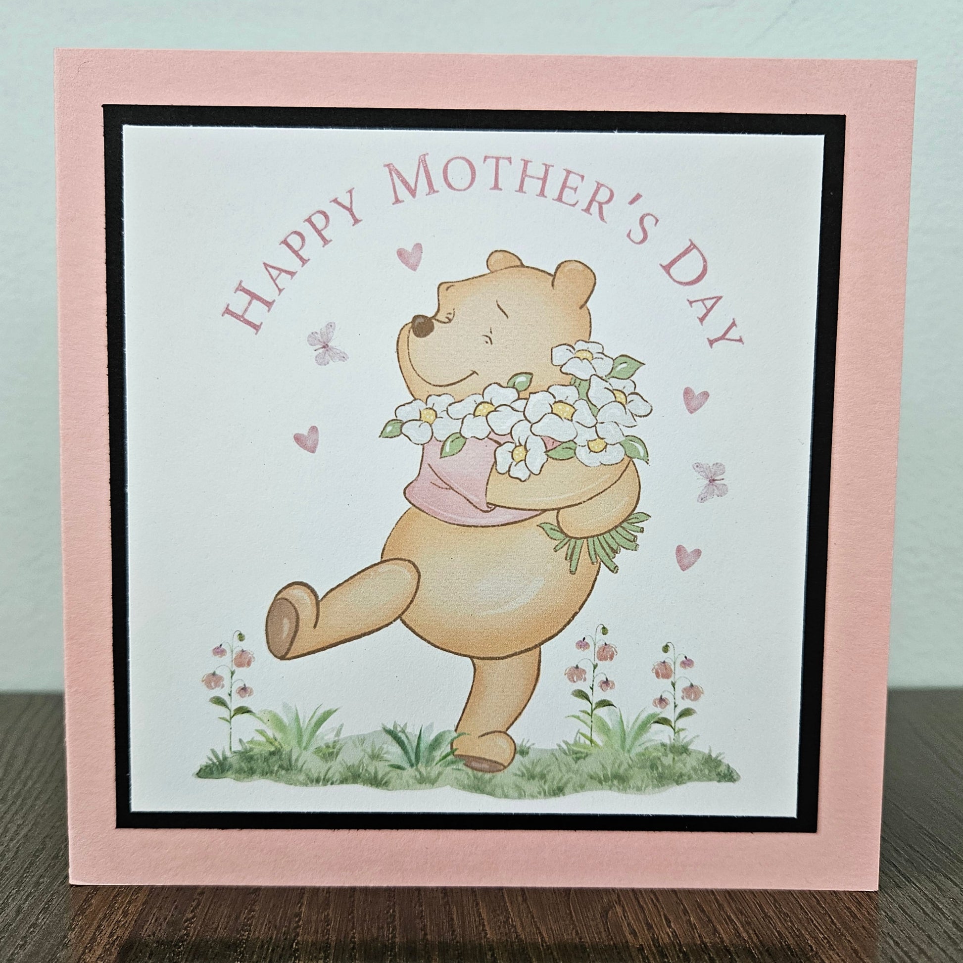 Handmade Winnie the Pooh Mother's Day card holding flowers on a pink border