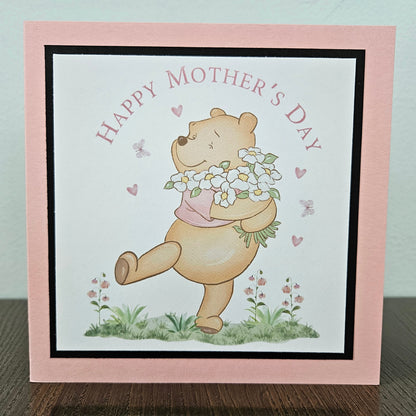 Handmade Winnie the Pooh Mother's Day card holding flowers on a pink border