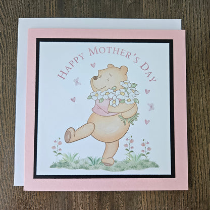 Handmade Winnie the Pooh Mother's Day card holding flowers on a pink border
