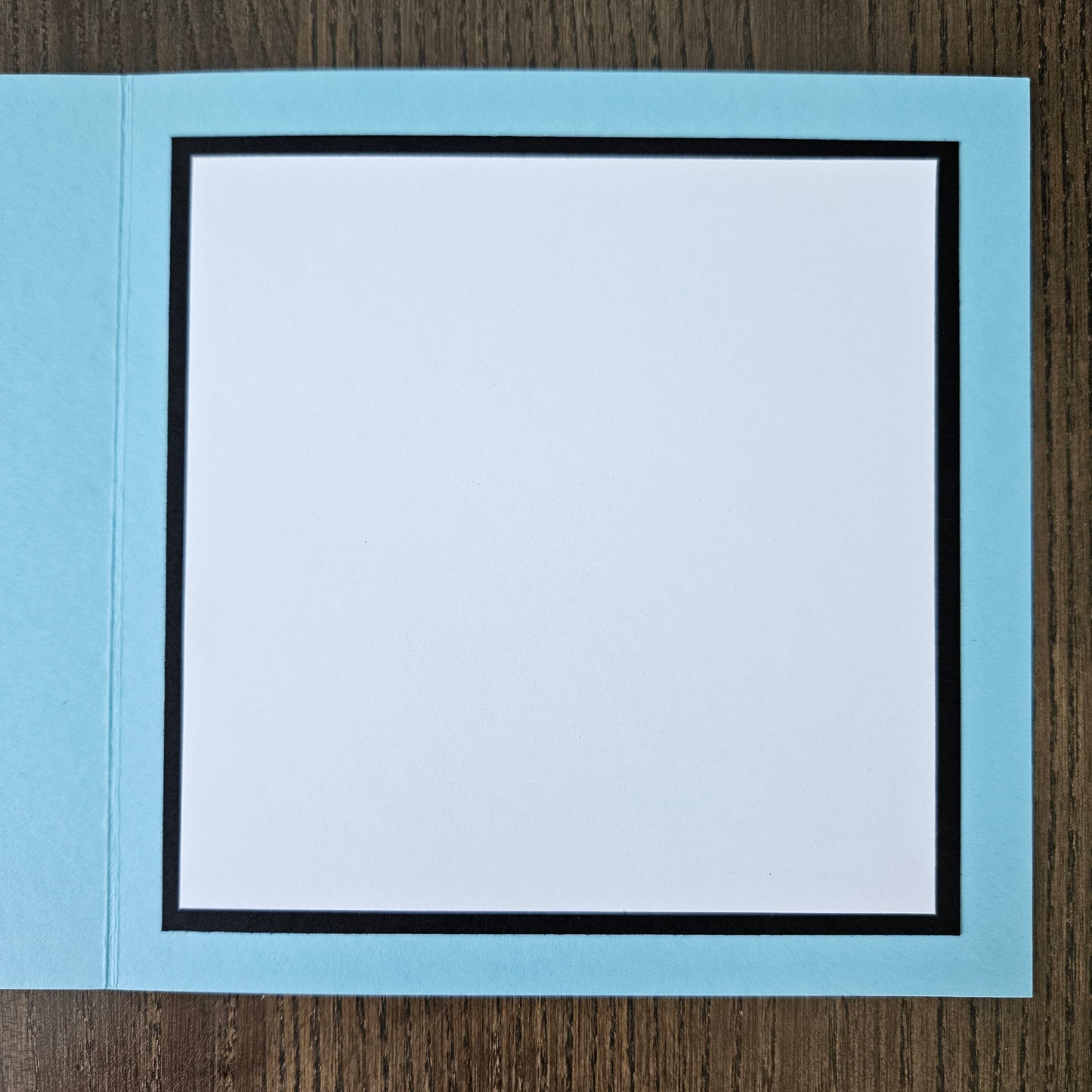 Light blue card with a white interior on a wooden surface