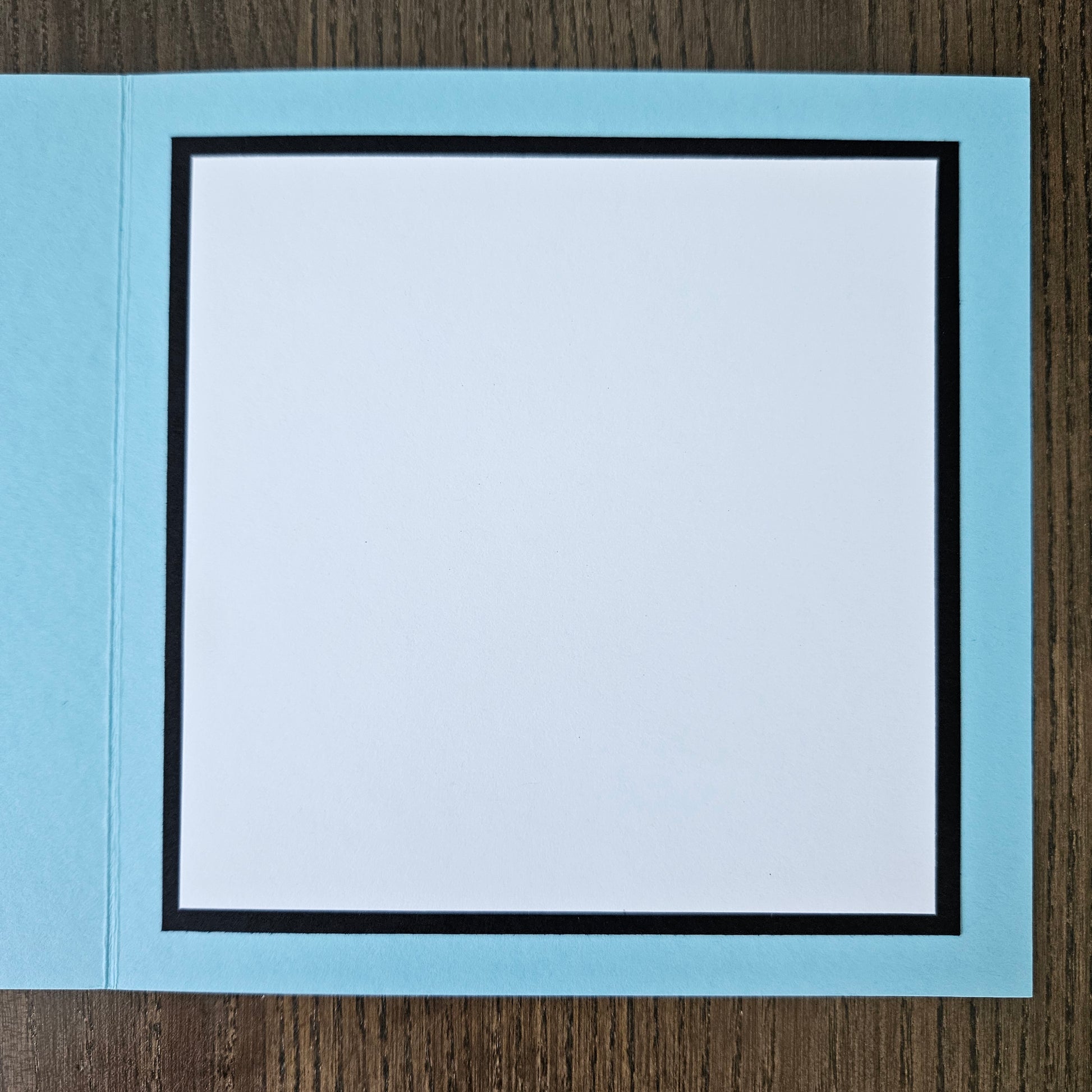 Light blue card with a white interior on a wooden surface