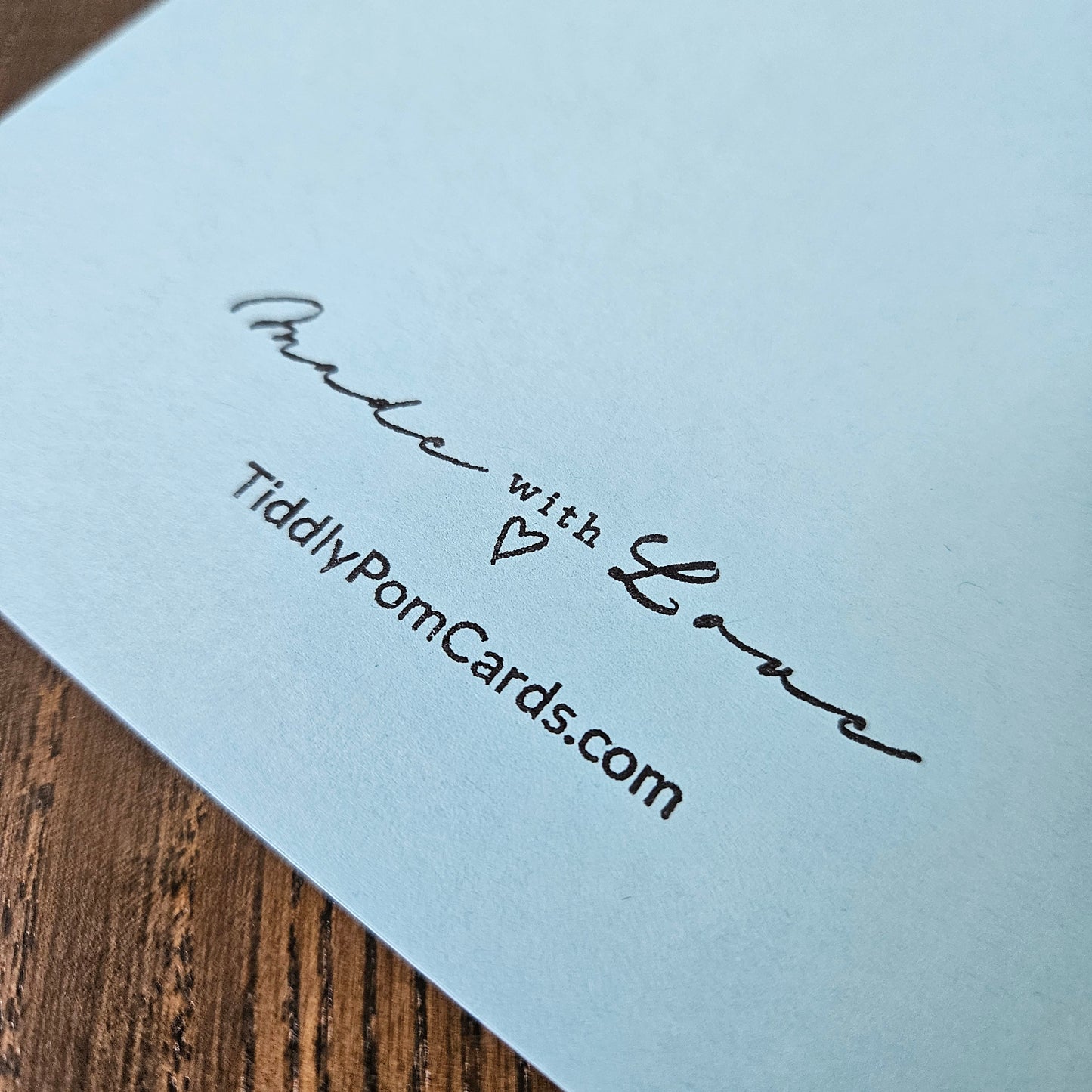 Light blue card with 'Made with Love' text and a heart symbol, on a wooden surface.