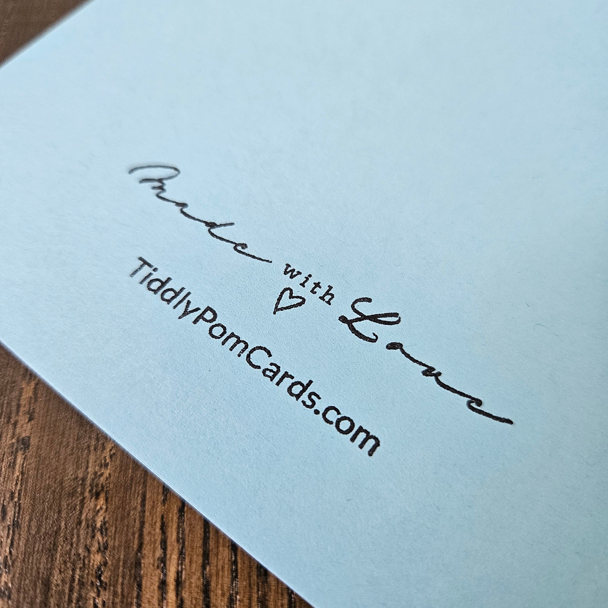 Light blue card with 'Made with Love' text and a heart symbol, on a wooden surface.