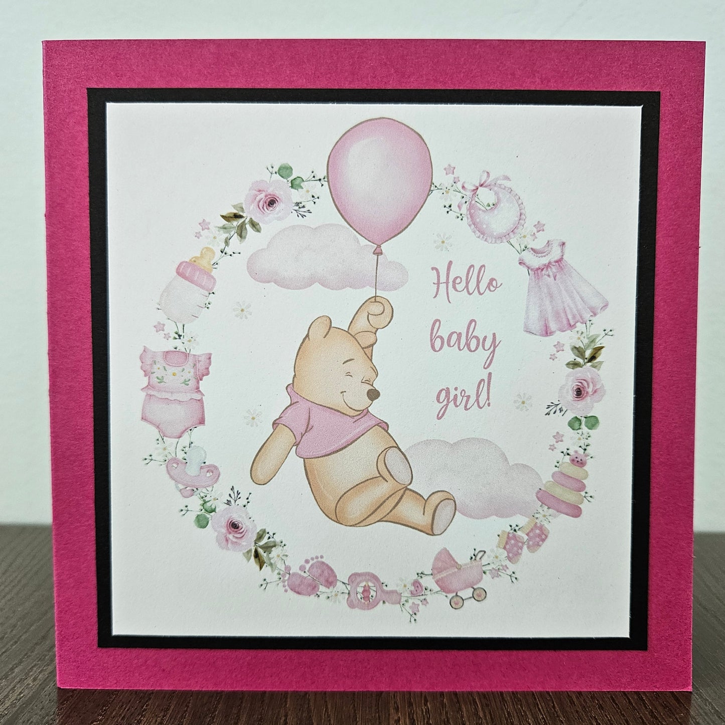 Baby shower card with Winnie the Pooh and baby-themed illustrations on a pink border.