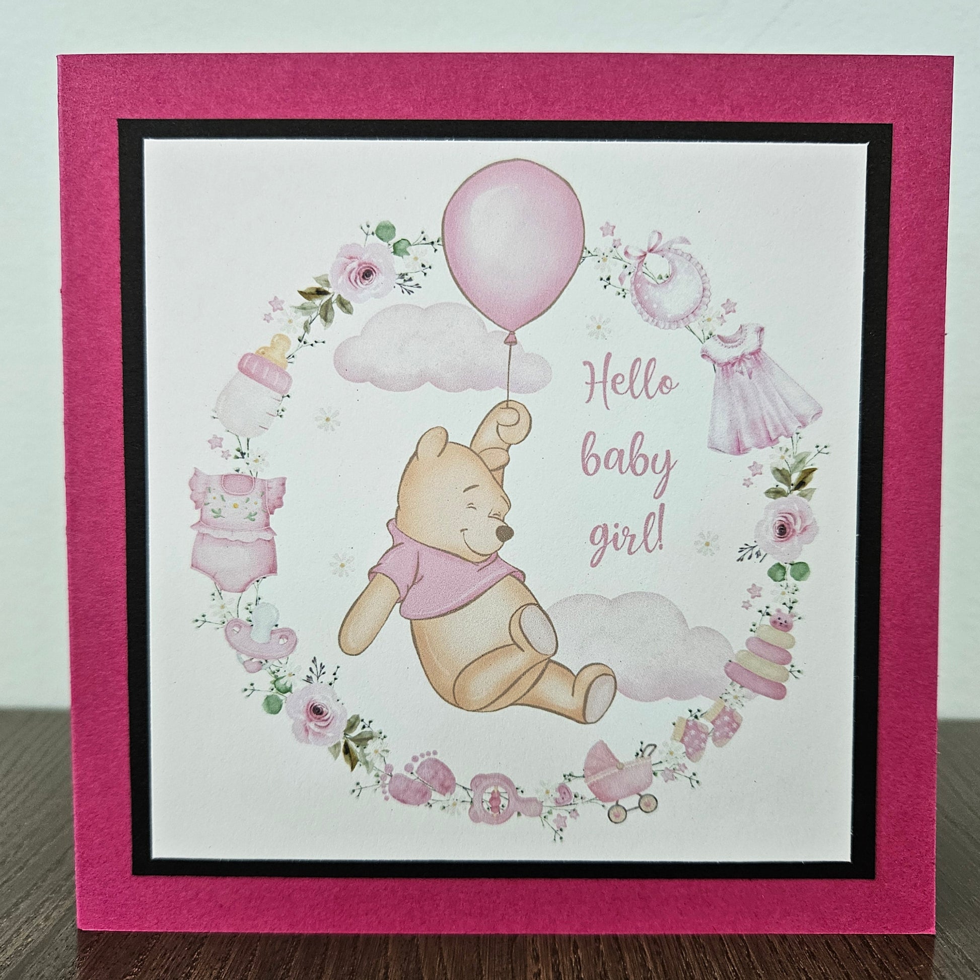 Baby shower card with Winnie the Pooh and baby-themed illustrations on a pink border.