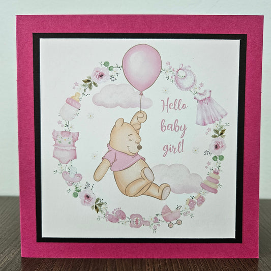 Baby shower card with Winnie the Pooh and baby-themed illustrations on a pink border.