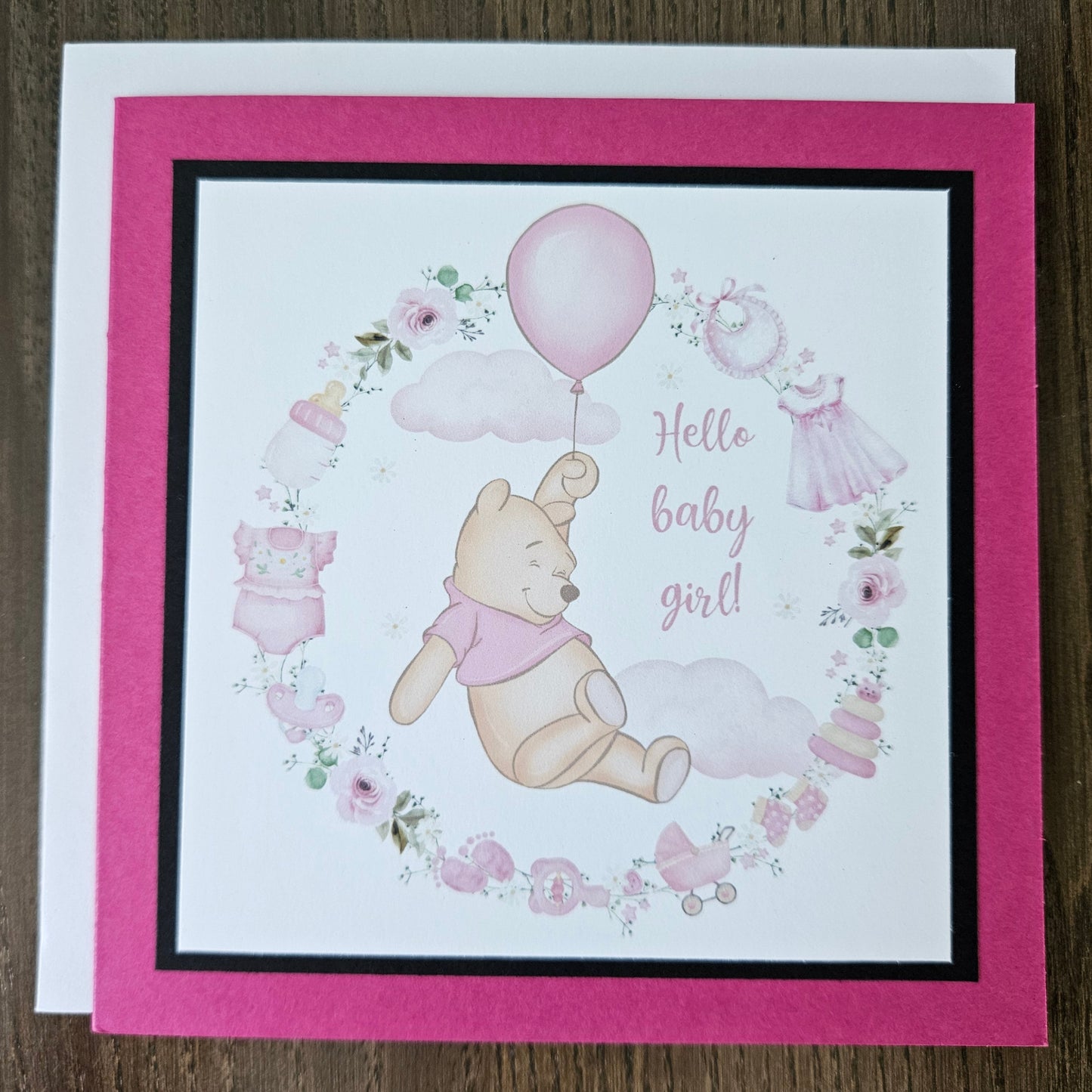 Baby shower card with Winnie the Pooh and balloons on a wooden surface