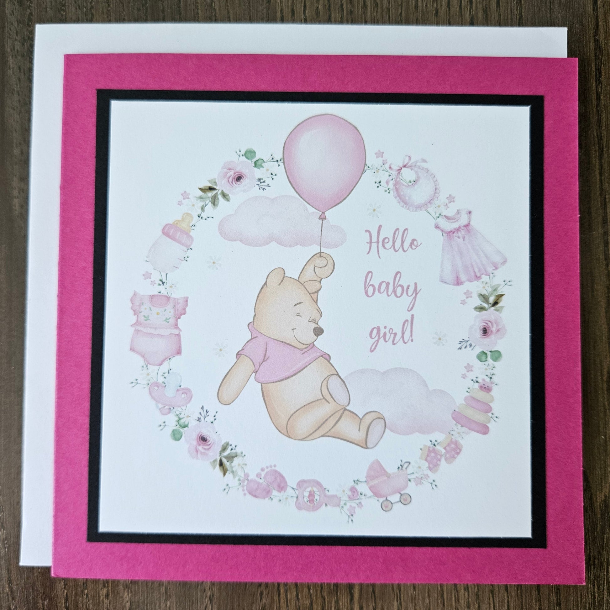 Baby shower card with Winnie the Pooh and balloons on a wooden surface