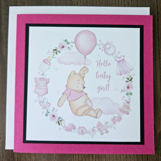 Baby shower card with Winnie the Pooh and balloons on a wooden surface