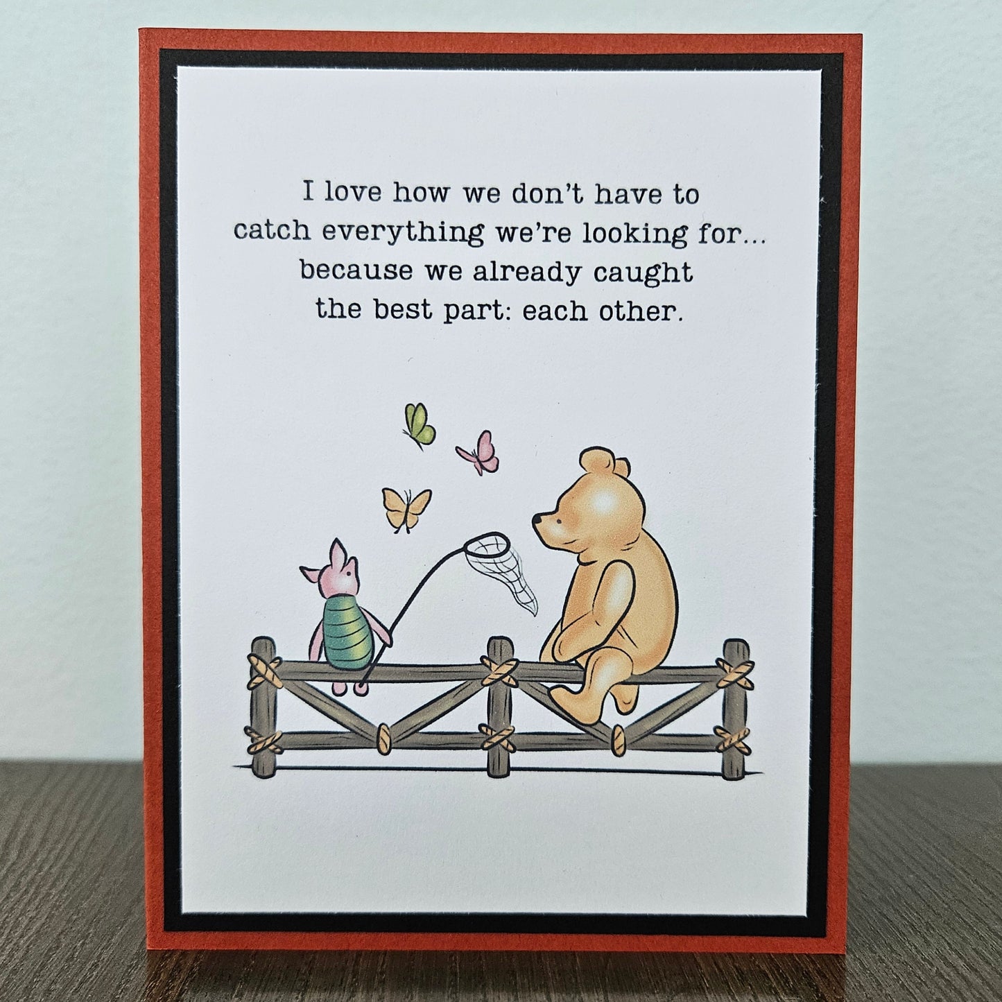 Handmade Winnie the Pooh friendship card featuring a classic storybook illustration of Pooh Bear and Piglet sitting together on a rustic wooden fence watching butterflies, finished with layered cardstock frames.