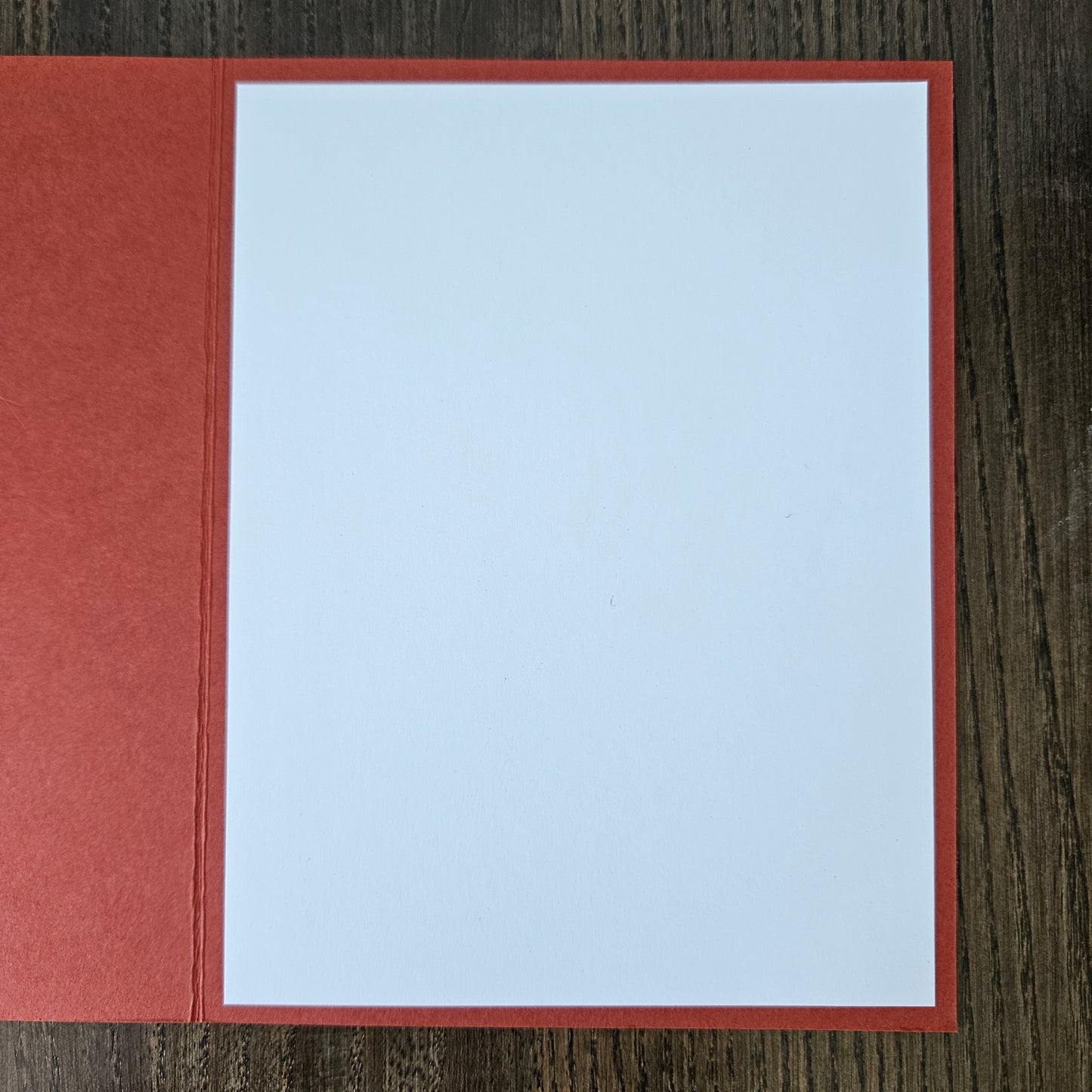 Red envelope with a white card inside on a wooden surface