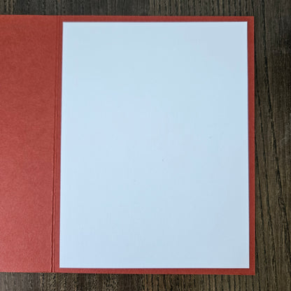 Red envelope with a white card inside on a wooden surface