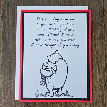 handmade A2 greeting card featuring a classic black ink sketch of Winnie the Pooh hugging Piglet, printed with a touching poem about sending a hug to show someone they are being thought of, framed with a bold black mat and a vibrant red card border.