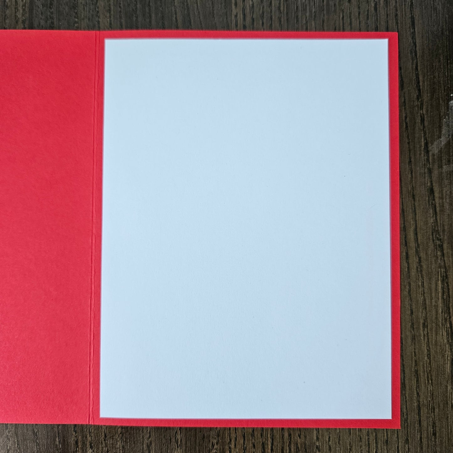 Red card with a white square in the center on a wooden surface