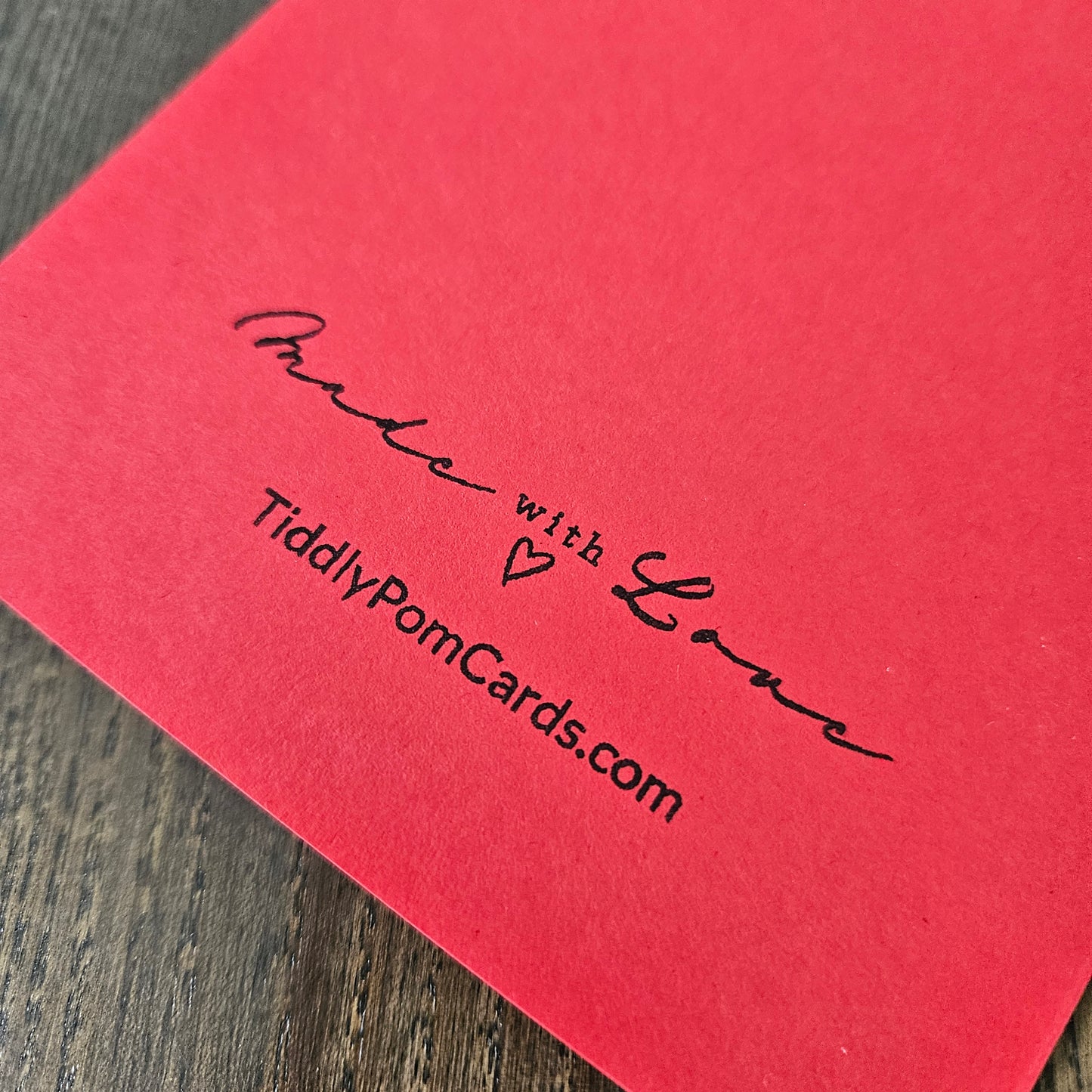 Red card with 'Made with Love' and 'TiddlyPomCards.com' text on a wooden surface
