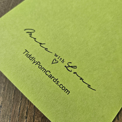 Green card with 'Made with Love' and 'TiddlyPomCards.com' text on a wooden surface