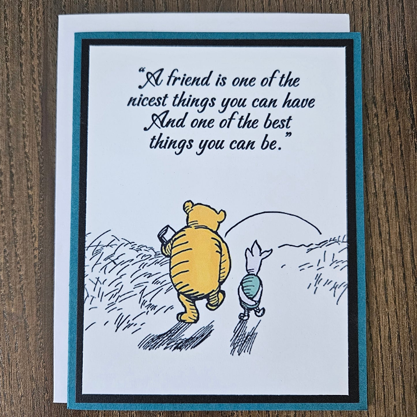 Greeting card with Winnie the Pooh and Piglet flying and a quote on a wooden surface