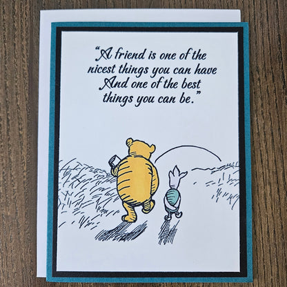 Greeting card with Winnie the Pooh and Piglet flying and a quote on a wooden surface