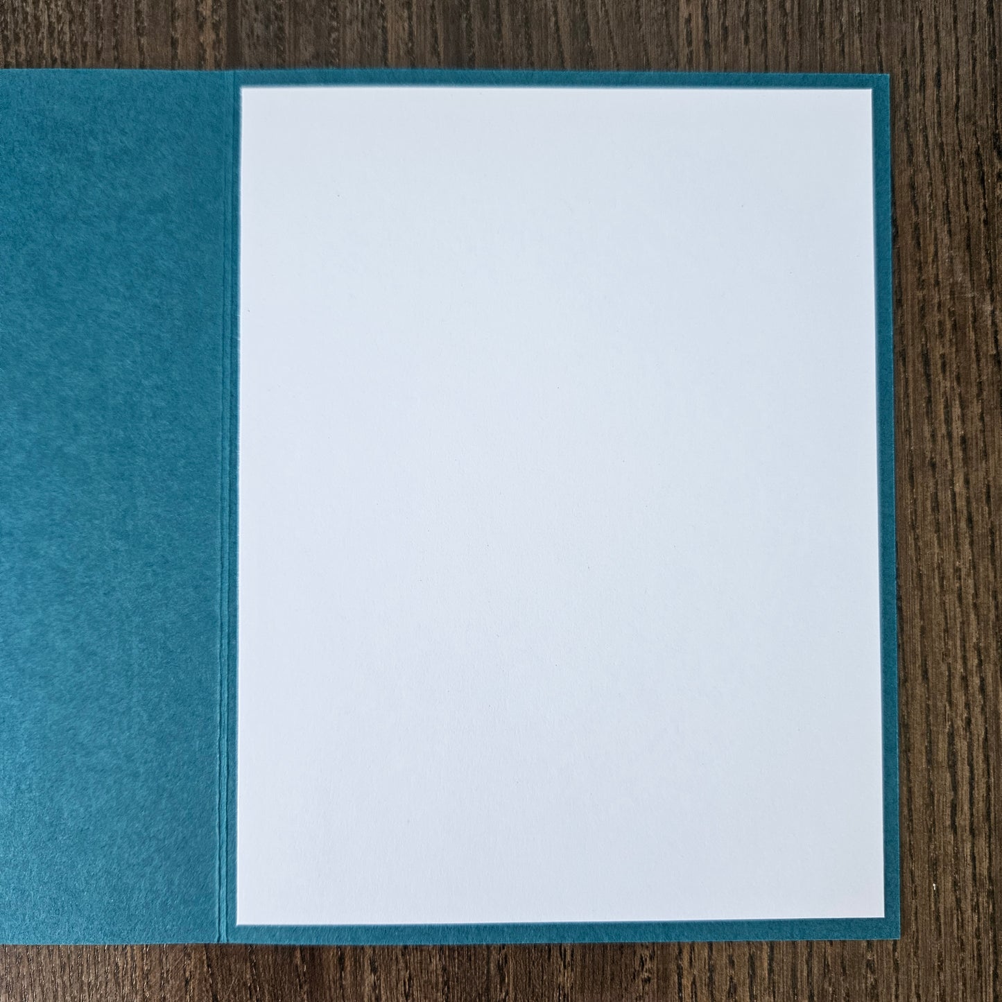 Blue envelope with a white card on a wooden surface